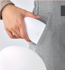 グレーのヘリンボーンのポケットに白い卵型ブラシデバイスを入れる手元